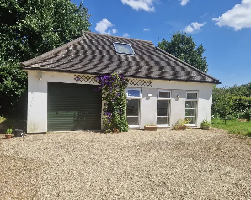 A converted detached garage with a roof window, new glazed doors and a climbing plant by the door