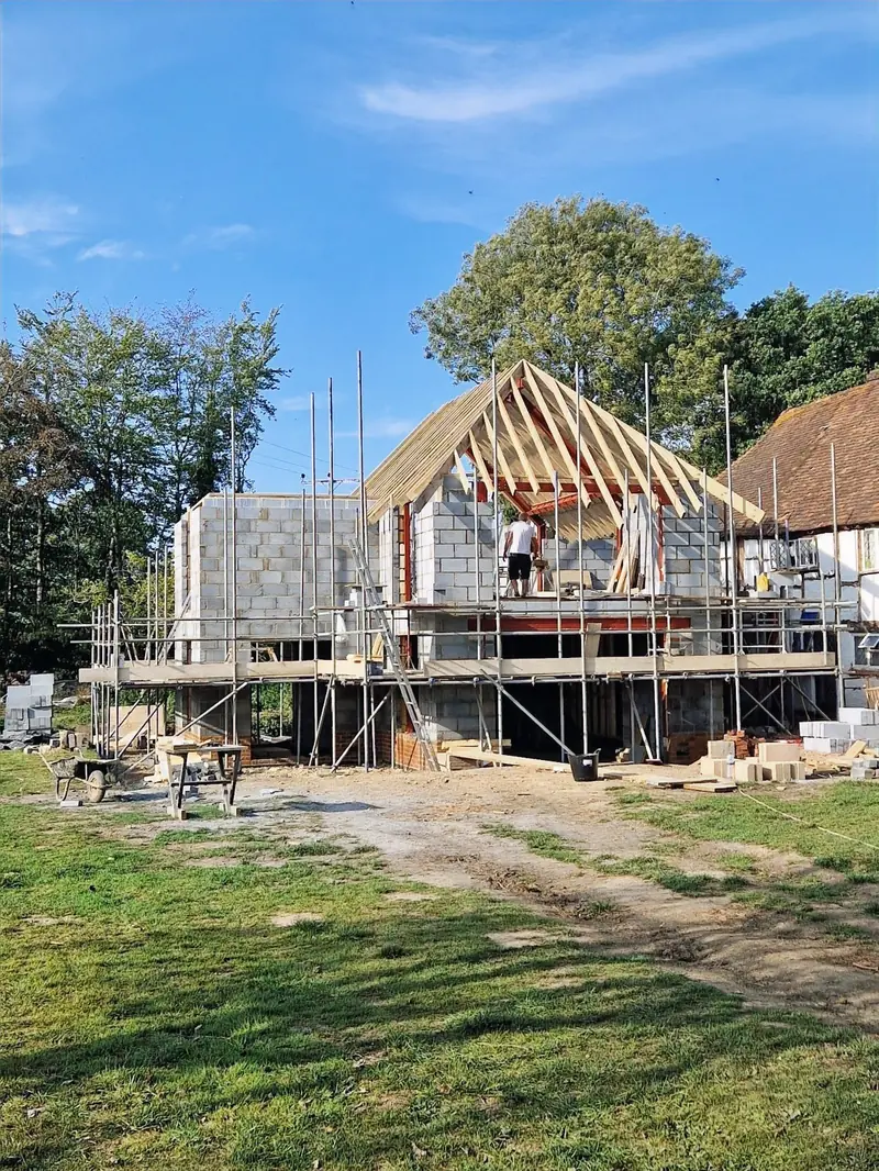 The timber roof frame going up on a new two-storey extension, seen from the garden